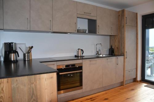 a kitchen with wooden cabinets and black counter tops at Our's Living - modern Apartments with Sauna near Kitzbüheler Alpen ski lift in Hollersbach im Pinzgau