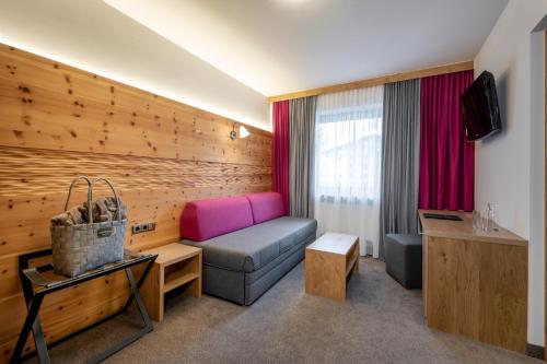 a hotel room with a couch and a tv at Ski & Bike Hotel Wiesenegg in Saalbach Hinterglemm