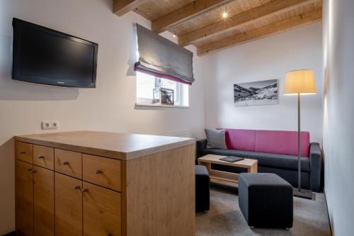 a living room with a couch and a flat screen tv at Ski & Bike Hotel Wiesenegg in Saalbach Hinterglemm
