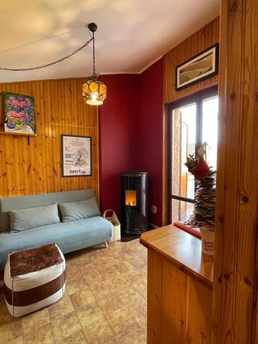 - un salon avec un canapé bleu et des murs rouges dans l'établissement Appartamento Le Betulle, à Erbezzo