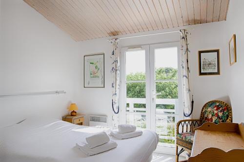 a white bedroom with a bed and a window at Charmante maison au coeur de Saint Martin in Saint-Martin-de-Ré