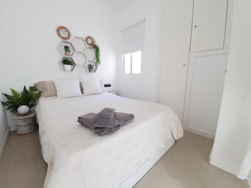 Un dormitorio blanco con una cama con una toalla. en Apartamento Alvarez, en Málaga