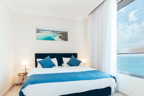 a bedroom with a bed with a view of the ocean at Almog Haifa Israel Apartments מגדלי חוף הכרמל in Haifa