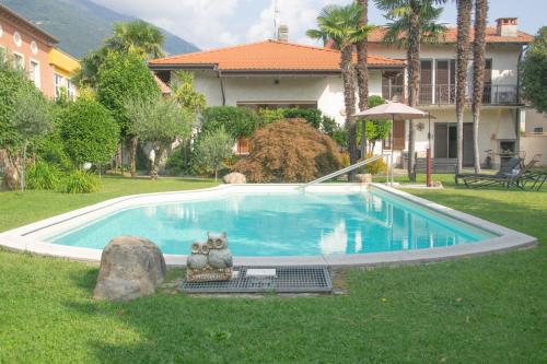 uma piscina com duas estátuas de gatos ao lado de uma casa em Villa Michelangelo - WelcHome em Cannobio