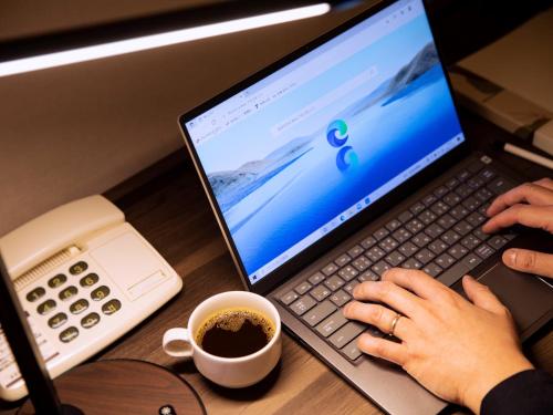 a person typing on a laptop computer with a cup of coffee at Business Inn Norte 2 in Sapporo