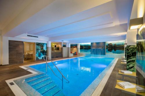 a large swimming pool with blue water in a building at Wohlfühlhotel Schiestl in Fügen