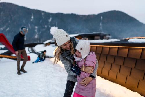 a woman holding a child in the snow at Falkensteiner Family Resort Lido Superior in Chienes