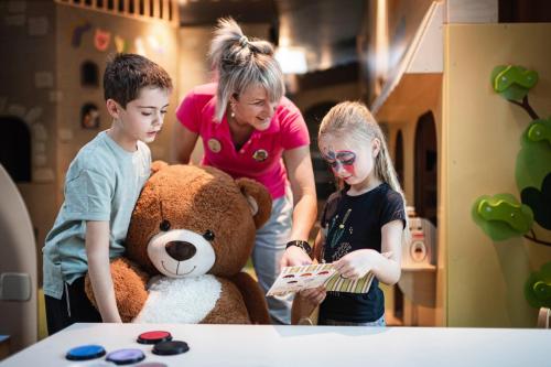 two children and a woman standing next to a teddy bear at Falkensteiner Family Resort Lido Superior in Chienes