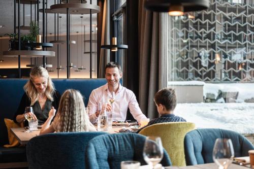 a group of people sitting around a table in a restaurant at Falkensteiner Family Resort Lido Superior in Chienes