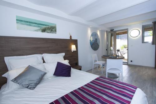 une chambre avec un grand lit blanc avec des oreillers violets dans l'établissement Pointe, à Saint-Cyr-sur-Mer