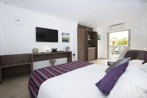 une chambre avec un lit blanc et une télévision dans l'établissement Rainette, à Saint-Cyr-sur-Mer