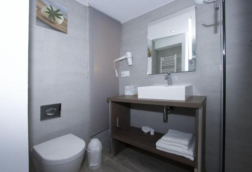 une salle de bain avec un lavabo, des toilettes et un miroir dans l'établissement Moutte, à Saint-Cyr-sur-Mer