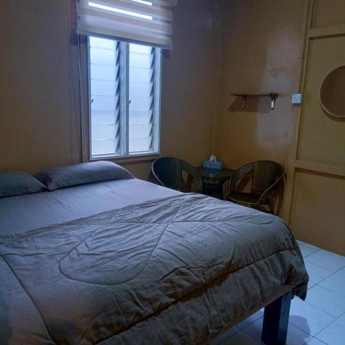 a bedroom with a bed and a window and a table at The Rustique Guest House in Tanah Rata