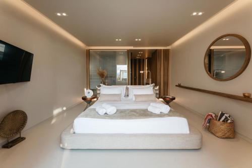 a bedroom with a large white bed and a mirror at Avgoustos Suites Naxos in Naxos Chora