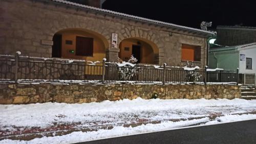 a building with a fence covered in snow at Casa Rural los Portalillos II in Navatalgordo