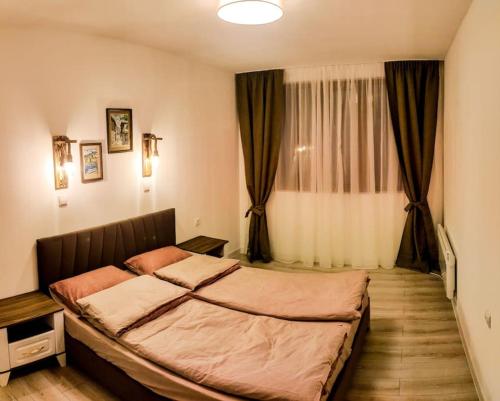 a bedroom with a large bed in front of a window at Луксозен Апартамент Мечи Чал - Апартхотел Манастира 2 in Pamporovo