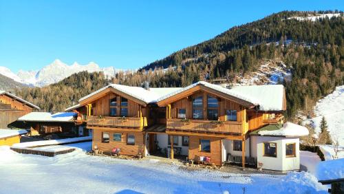 a large wooden house with snow on the roof at Öko-Appartements Fallhaus in Forstau