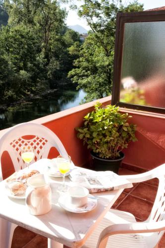 a white table with two chairs and wine glasses at Hotel Covadonga in Cangas de Onís