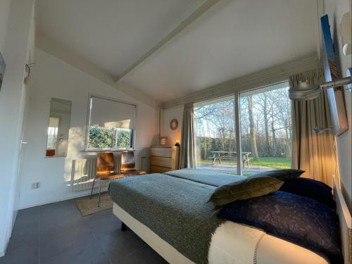 a bedroom with a bed and a large window at Vakantiehuis Zonlicht in Zoutelande