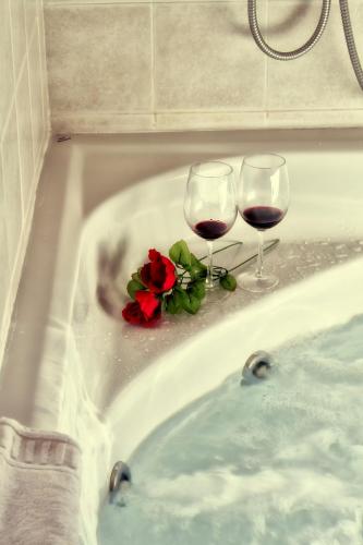 two glasses of wine and a rose in a bath tub at Hotel Covadonga in Cangas de Onís