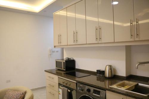 a kitchen with white cabinets and a microwave at Executive Apartments in Amman