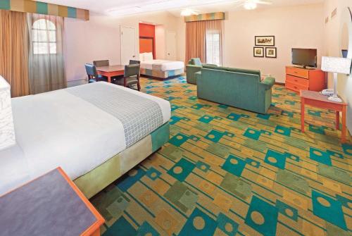 a hotel room with a bed and a dining room at Baymont by Wyndham Lubbock - Downtown Civic Center in Lubbock