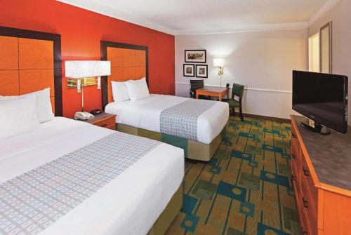 a hotel room with two beds and a flat screen tv at Baymont by Wyndham Lubbock - Downtown Civic Center in Lubbock