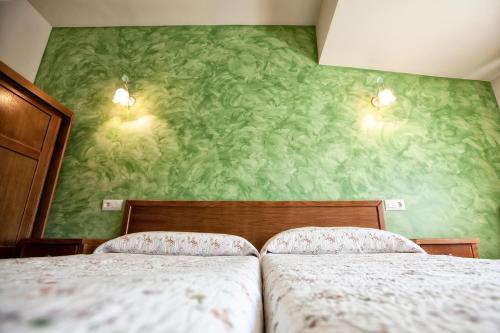two beds in a bedroom with green wallpaper at Hotel Covadonga in Cangas de Onís