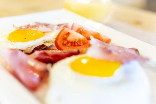 a plate of breakfast food with eggs and tomatoes at Hotel Alegra in Livigno
