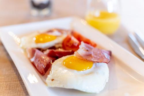 a plate of food with eggs and tomatoes on a table at Hotel Alegra in Livigno