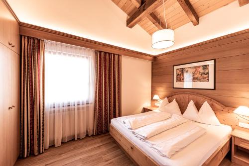a bedroom with a bed and a window at Aparthotel Kastel Seiser Alm in Castelrotto
