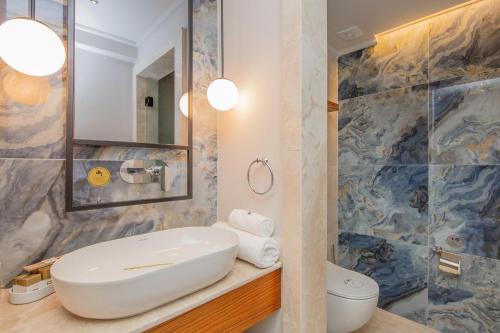 a bathroom with a sink and a toilet and a mirror at Orka World Hotel & Aquapark in Oludeniz