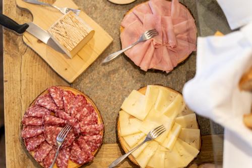 a table topped with cheese and meats and forks at Hotel Alegra in Livigno