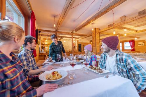 a group of people sitting around a table eating food at Hotel Alegra in Livigno
