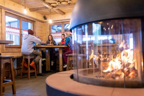 a group of people sitting at a bar with a fireplace at Hotel Alegra in Livigno