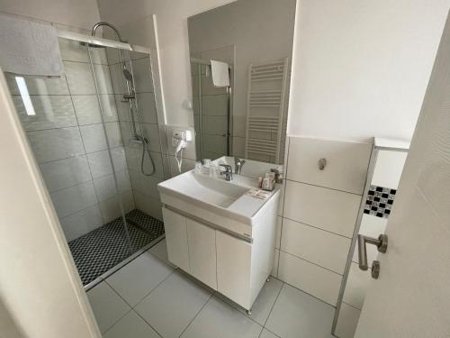 La salle de bains blanche est pourvue d'un lavabo et d'une douche. dans l'établissement ALPIN rooms, à Topliţa