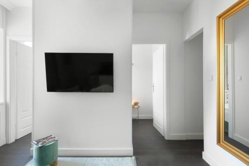 a living room with white walls and a television on a wall at Elite Apartments Old Town Deluxe in Gdańsk