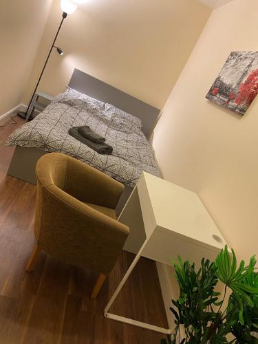a bedroom with a bed and a chair and a table at Cosy Ealing Homestay in London