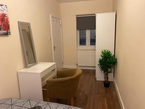 Cette chambre comprend un bureau, un miroir et une chaise. dans l'établissement Cosy Ealing Homestay, à Londres