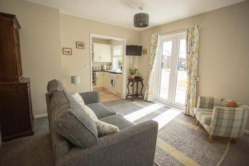 a living room with a gray couch and a kitchen at Pant-Y-Celyn Studio Apartment in Aberaeron