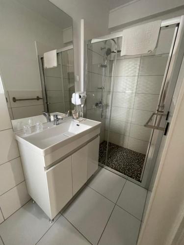 a white bathroom with a sink and a shower at ALPIN rooms in Topliţa