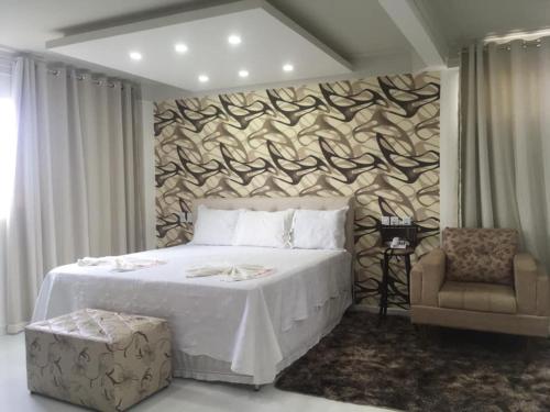 - une chambre avec un grand lit blanc et une chaise dans l'établissement Hotel Mirante B, à Euclides da Cunha