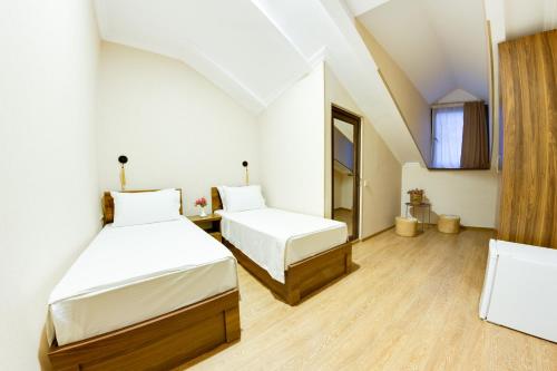 twee bedden in een kamer met witte muren en houten vloeren bij Sina Hotel in Tbilisi City