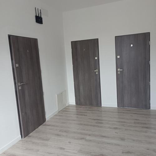 twee houten deuren in een kamer met houten vloeren bij Apartament Centrum Szczytno III in Szczytno