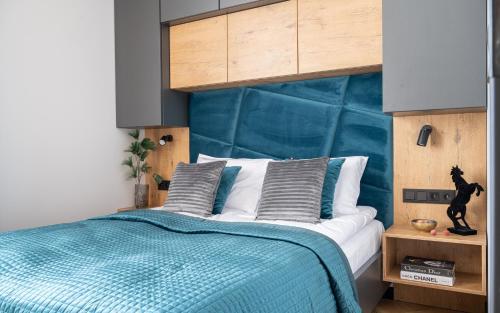 a bedroom with a bed with a blue headboard at Wrota Chałubińskiego in Zakopane