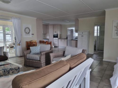 a living room with a couch and chairs and a kitchen at Pearly Waves in Pearly Beach