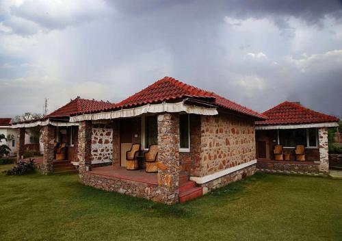a brick house with a red roof with a green yard at Virat Resorts, Sariska Rajasthan in Bairāt