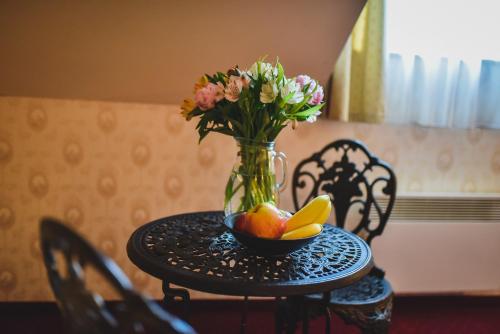 a vase with flowers and fruit on a table at Zámek Kamenný Dvůr in Kynšperk nad Ohří