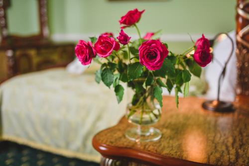 a vase filled with red roses on a table at Zámek Kamenný Dvůr in Kynšperk nad Ohří