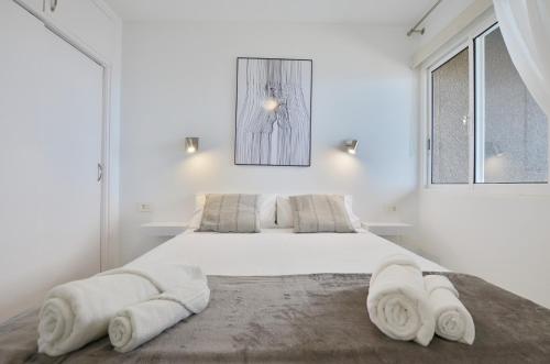 Un dormitorio blanco con una cama grande con toallas. en Costa Isora, en Puerto de Santiago